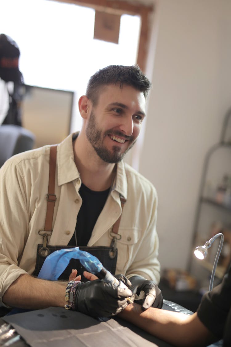 Man In Beige Button Up Shirt Holding Tattoo Pen