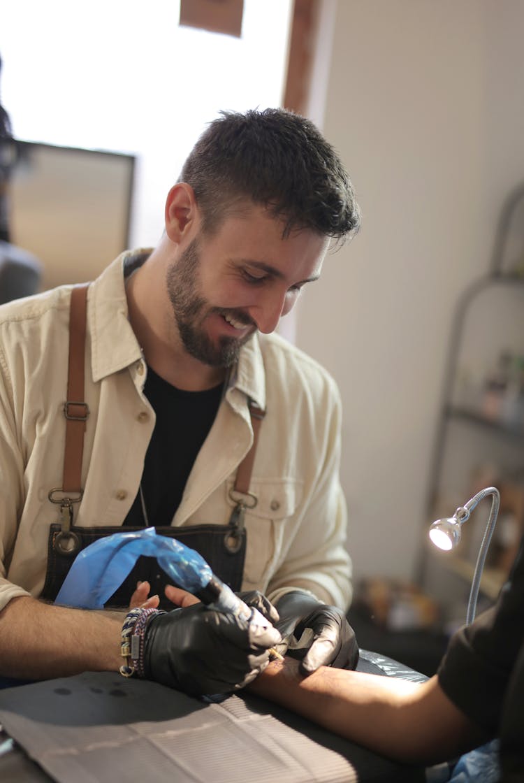 Man In Beige Button Up Shirt Holding Tattoo Pen