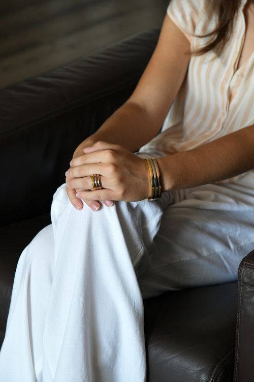 Free Close-up of a woman's hands adorned with jewelry, resting on her lap in casual attire. Stock Photo