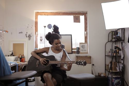 Free A young woman practicing guitar in a cozy indoor setting, expressing musical creativity. Stock Photo