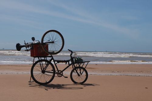 Free A bicycle parked on a sunny beach with ocean waves in the background, serene and quiet. Stock Photo