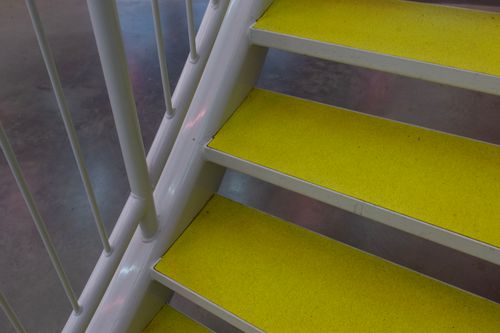 Free Detailed view of bright yellow staircase steps with metal railing indoors. Stock Photo