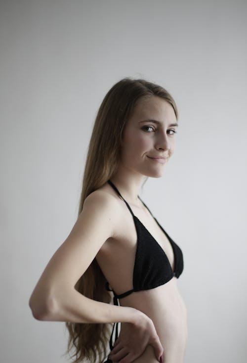 Woman in Black Bikini Standing Near White Wall