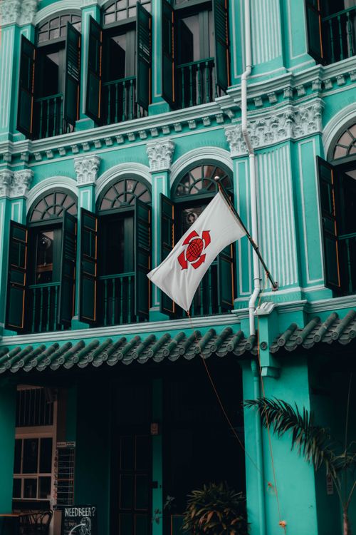Free A beautiful teal colonial building facade with open windows and flag. Stock Photo
