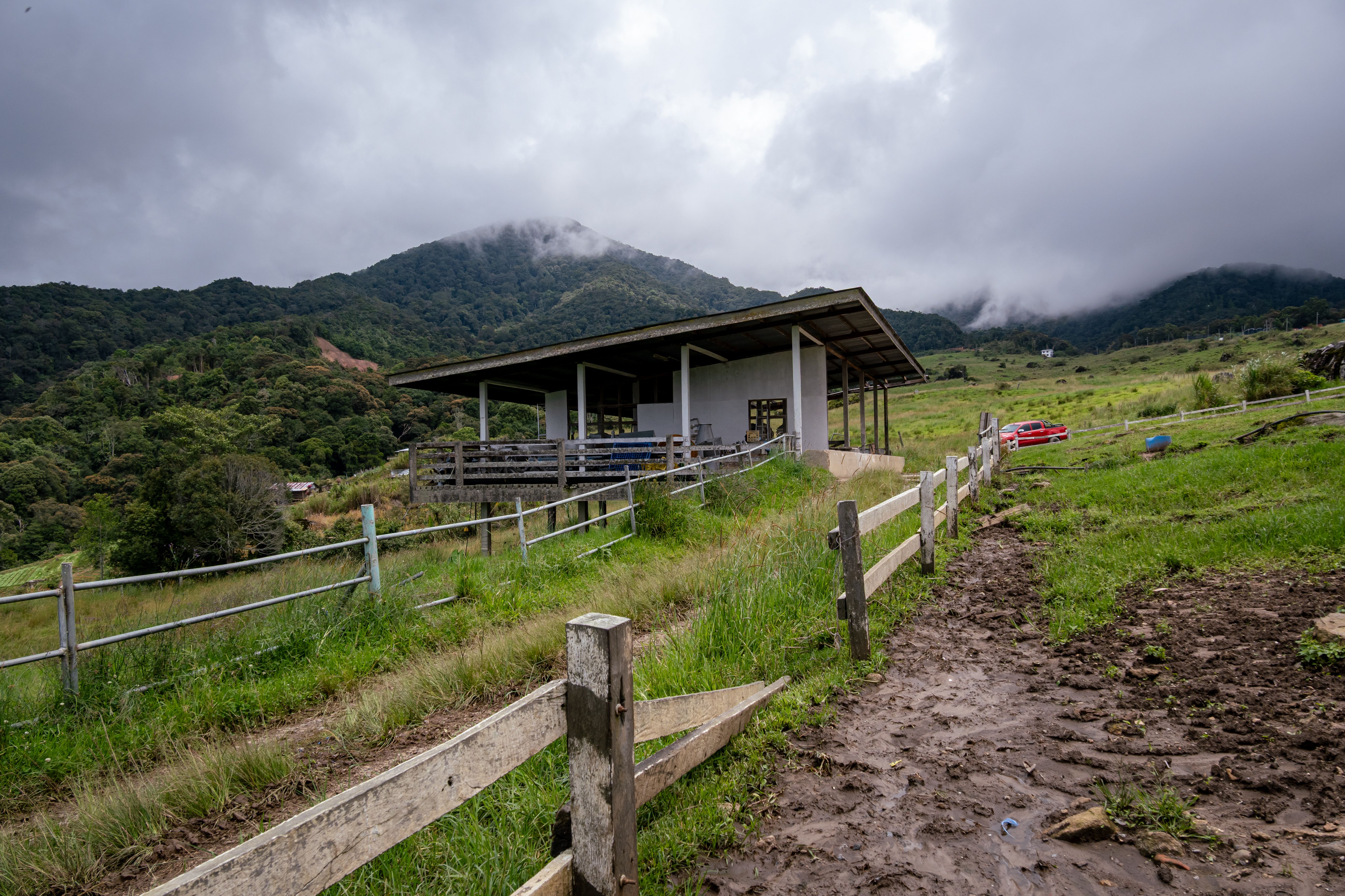 Charming rural farmhouse set against lush, misty mountains under a cloudy sky.