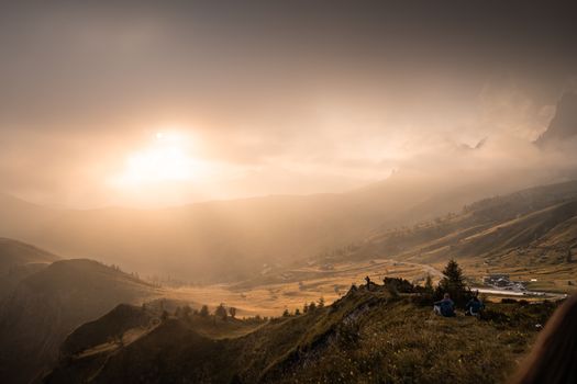 Golden sunset over Trentino-Südtirol mountains with serene landscapes and distant figures.