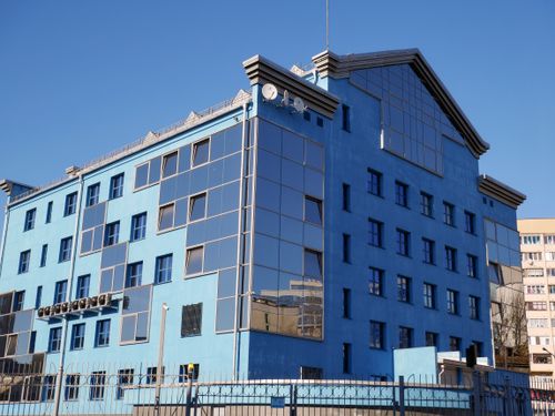Free Bright day view of a modern blue glass office building with unique architecture and rooftop structures. Stock Photo