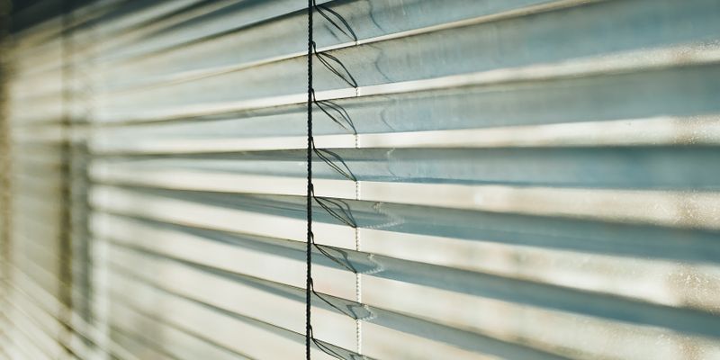 White venetian blinds with light streaming through the slats