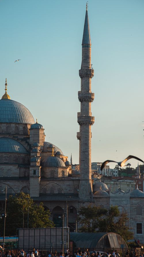 Free A serene view of the historical Yeni Cami Mosque in Istanbul during sunset with birds soaring. Stock Photo
