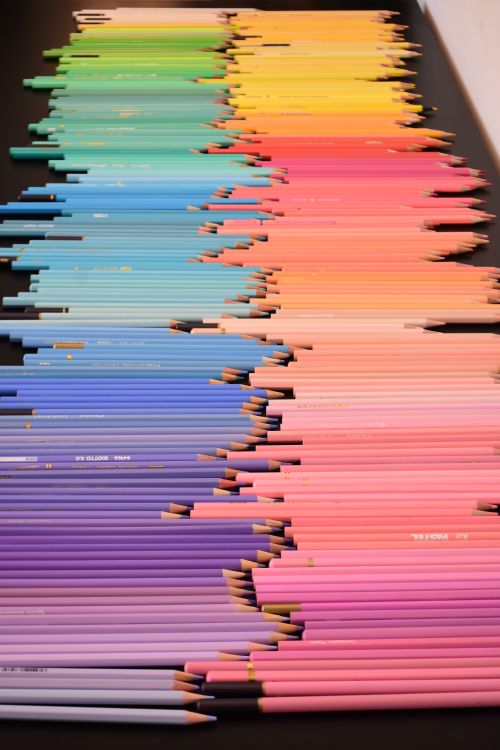 Free Vibrant array of colored pencils arranged in a gradient pattern on a black surface. Stock Photo