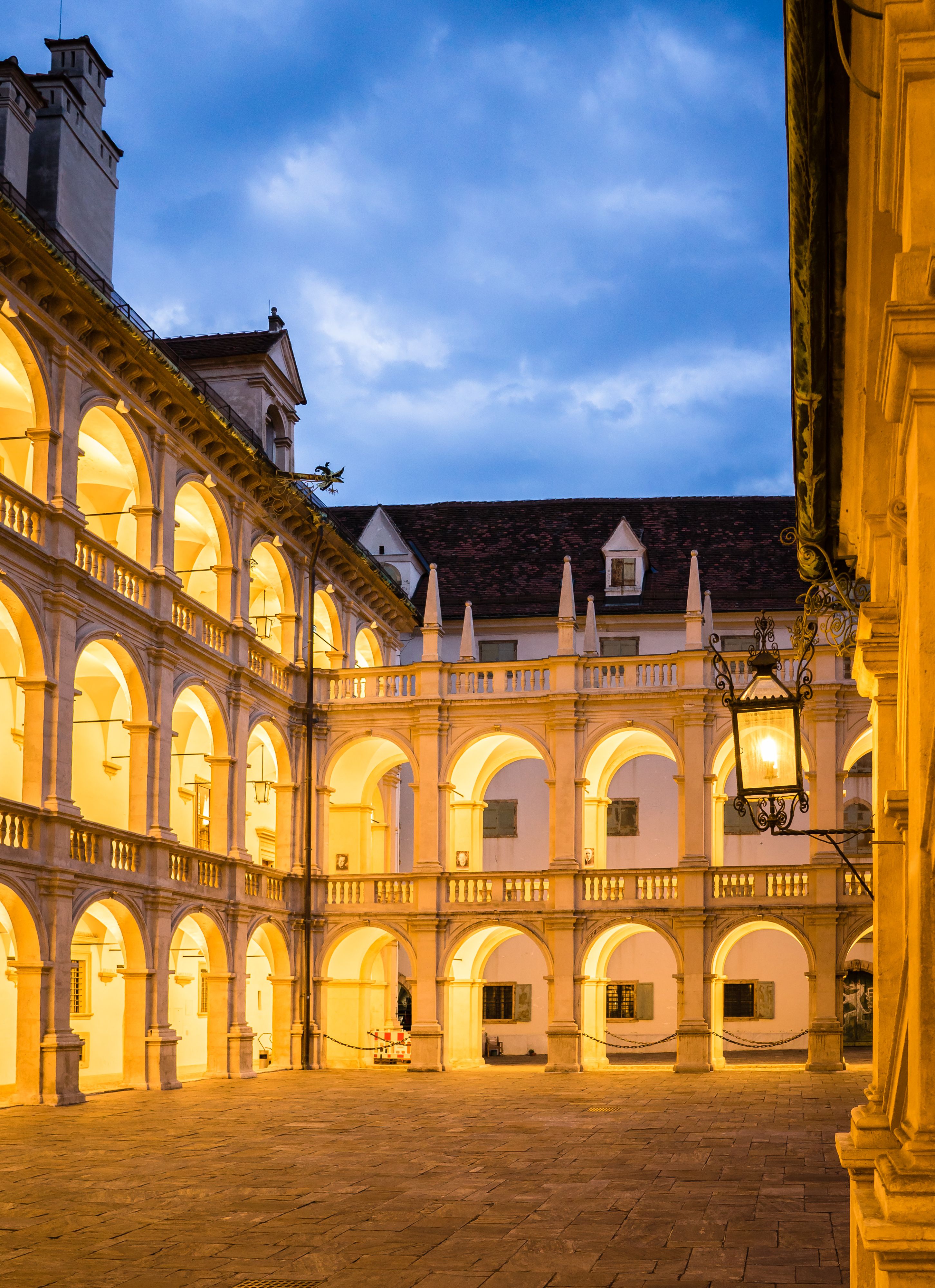 Beautifully lit Landhaus courtyard in Graz, Austria showcasing Renaissance architecture at dusk.