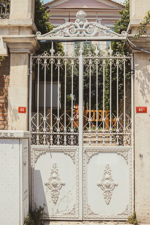 Free Elegant wrought iron gate entryway to a historic building with decorative motifs, bathed in sunlight. Stock Photo