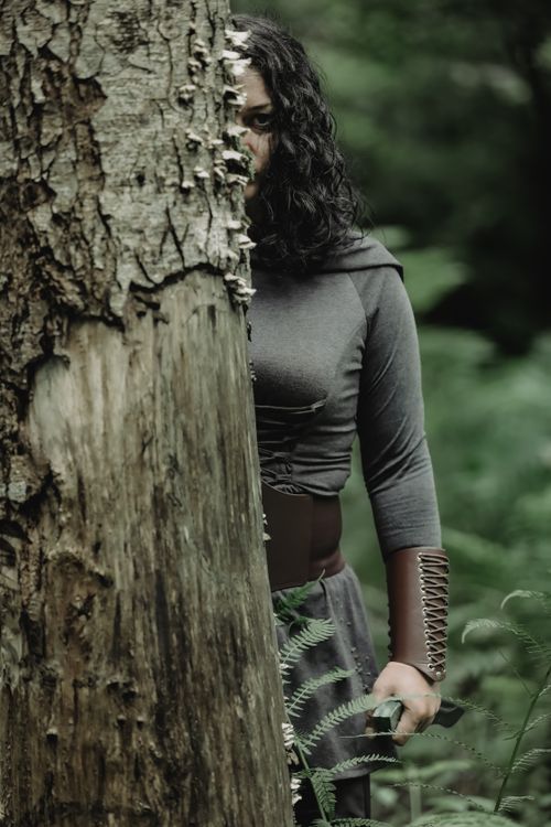 Free A mysterious figure partially hidden behind a tree in a lush forest. Stock Photo