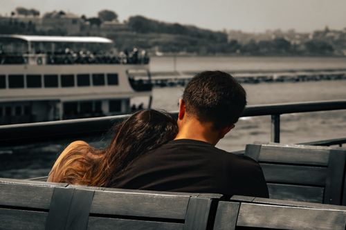 Free A couple shares a tender moment on a boat with a scenic waterfront view. Stock Photo