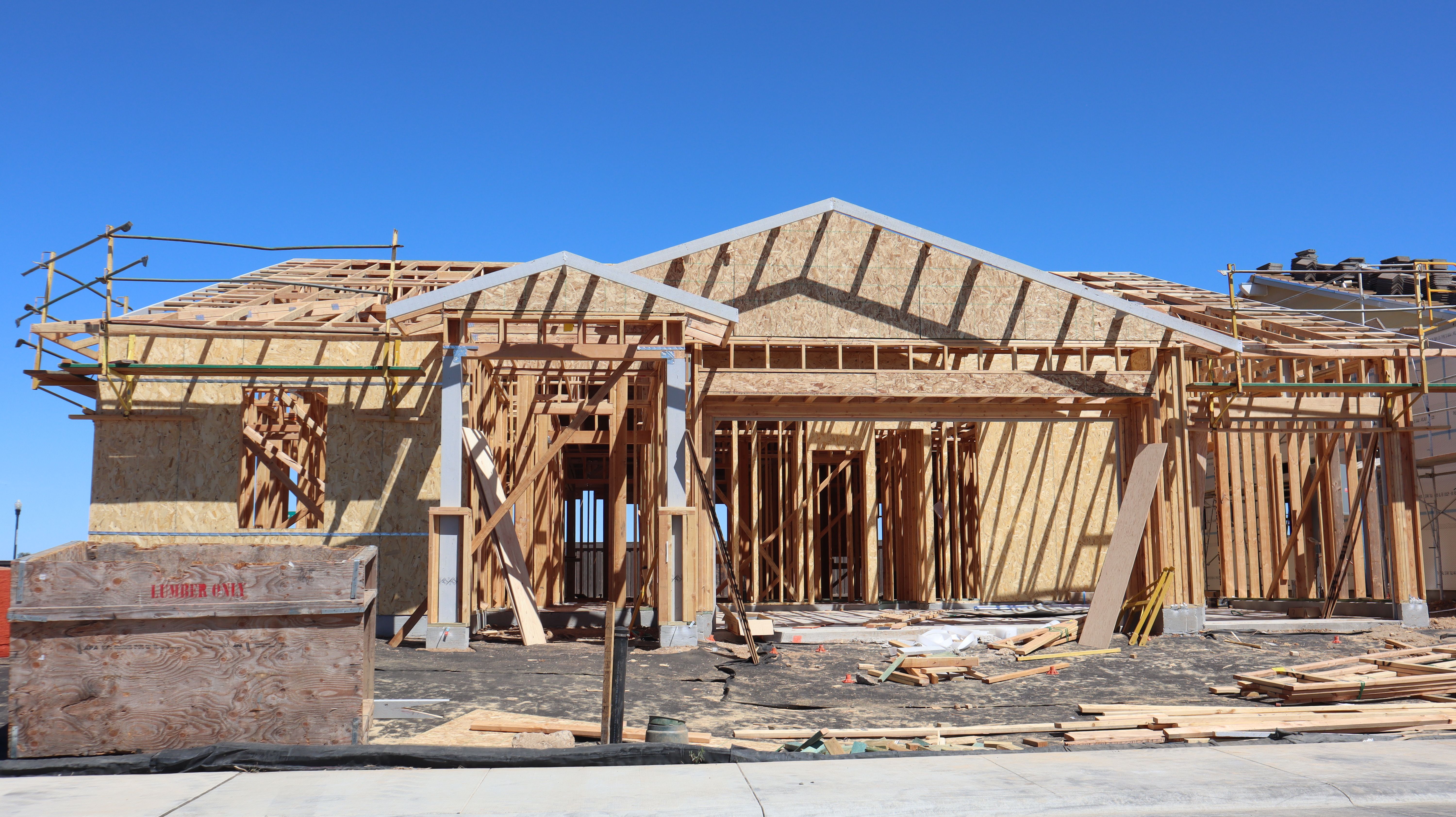 Wooden frame construction of a new residential home under clear blue sky.