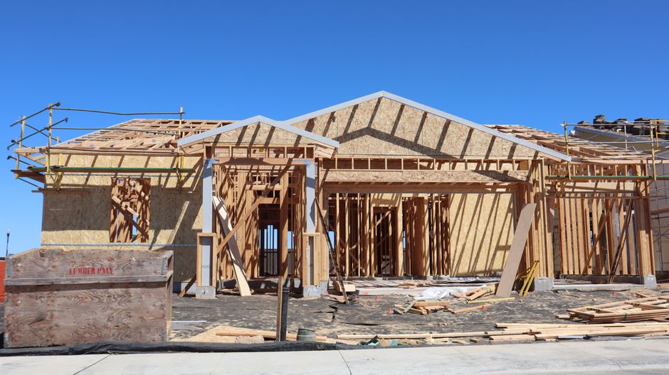 Photo by D Goug on Pexels Wooden frame construction of a new residential home under clear blue sky.