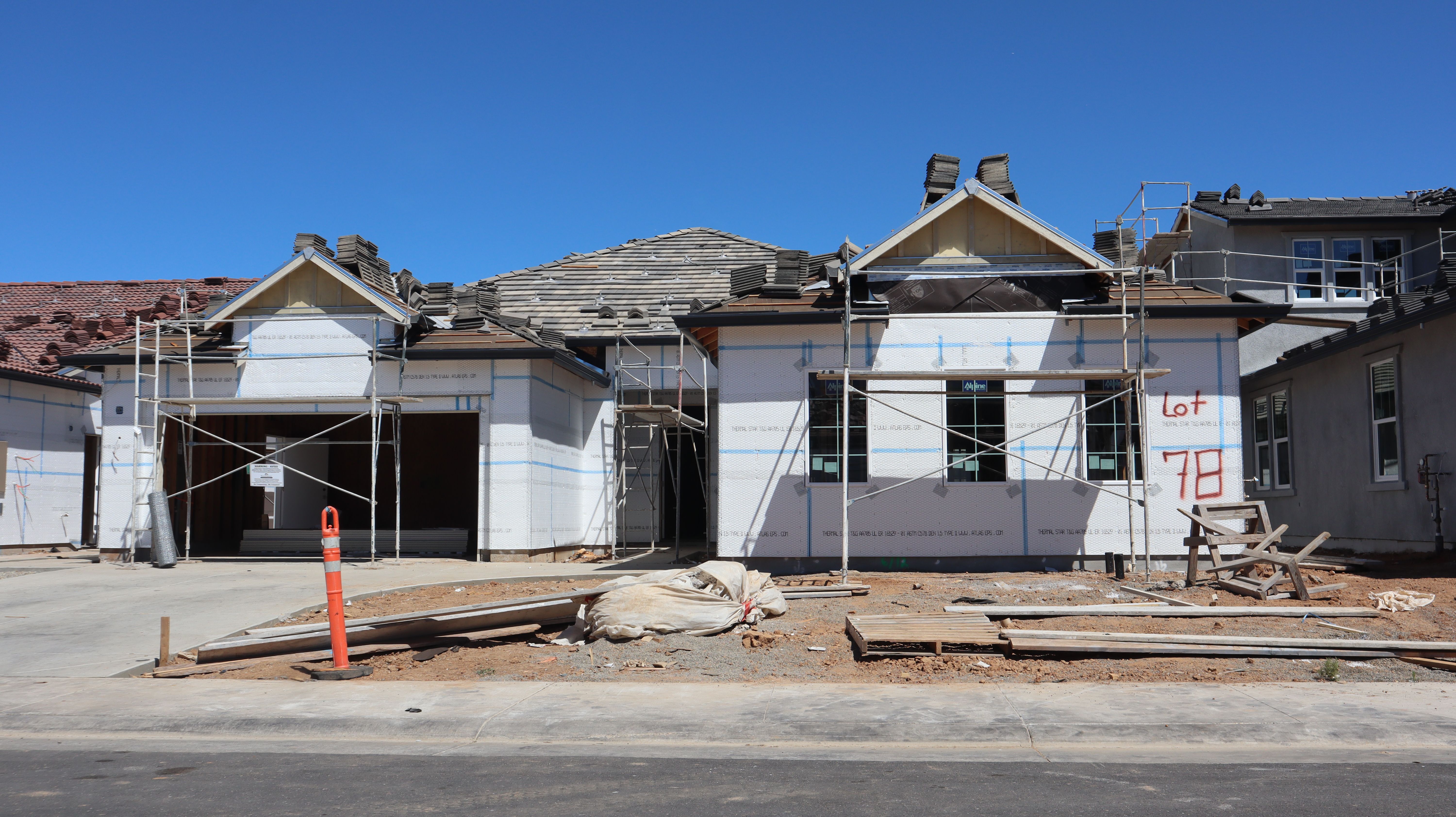 Front view of a single-family home under construction with scaffolding and materials.