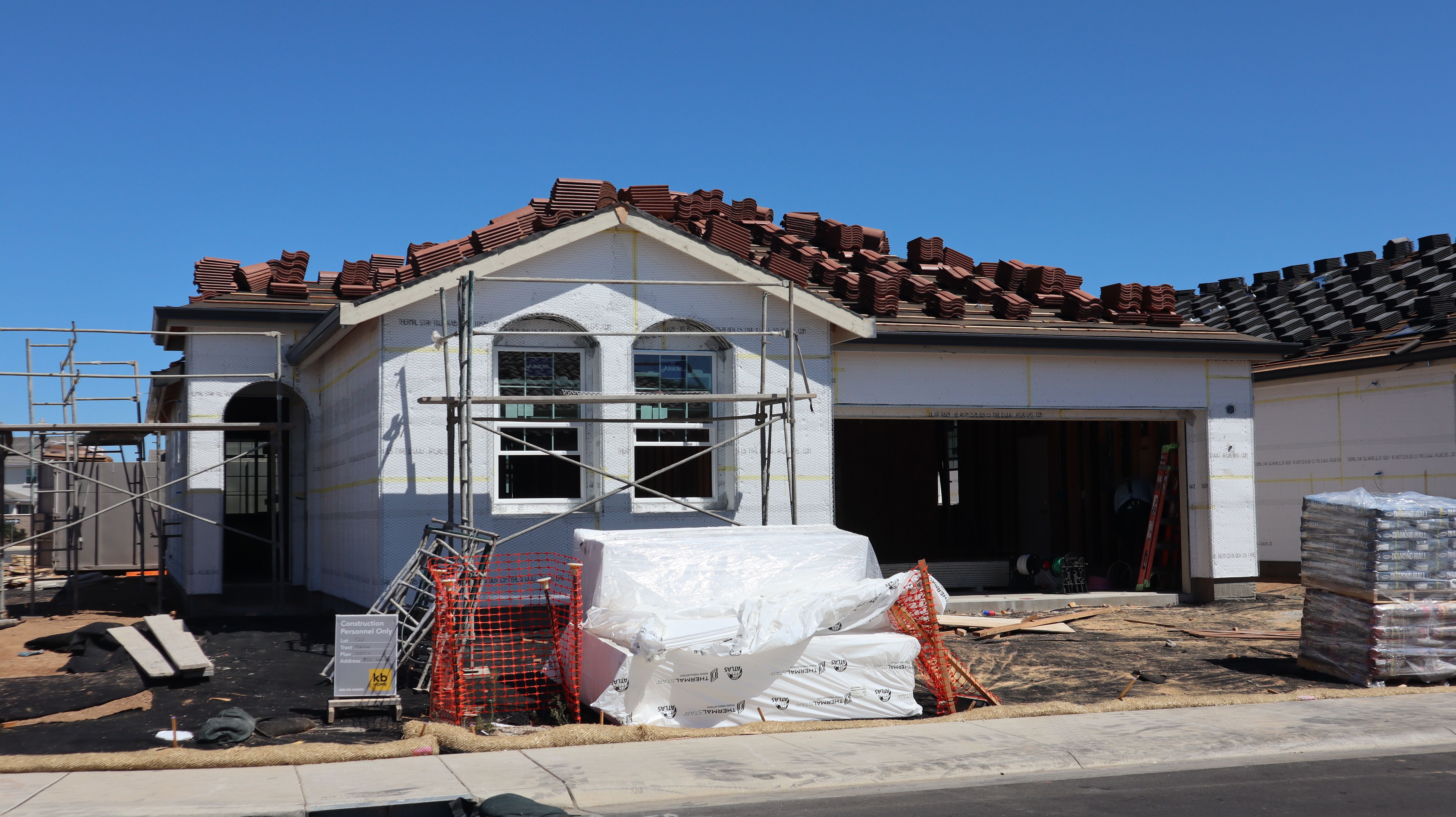 A newly constructed house under construction with roofing materials on top.
