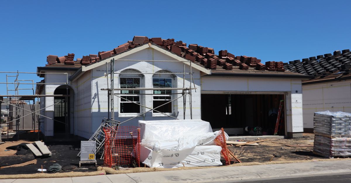 A newly constructed house under construction with roofing materials on top.