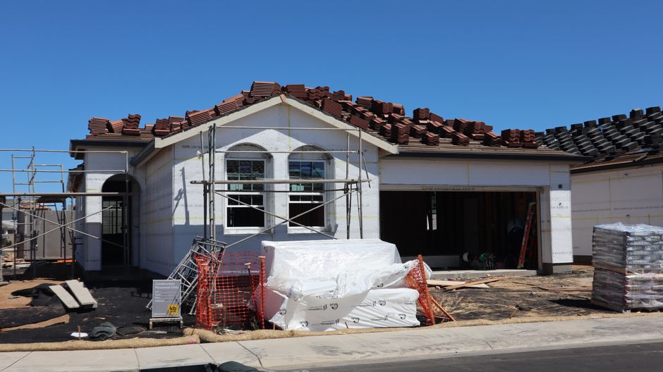 A newly constructed house under construction with roofing materials on top.