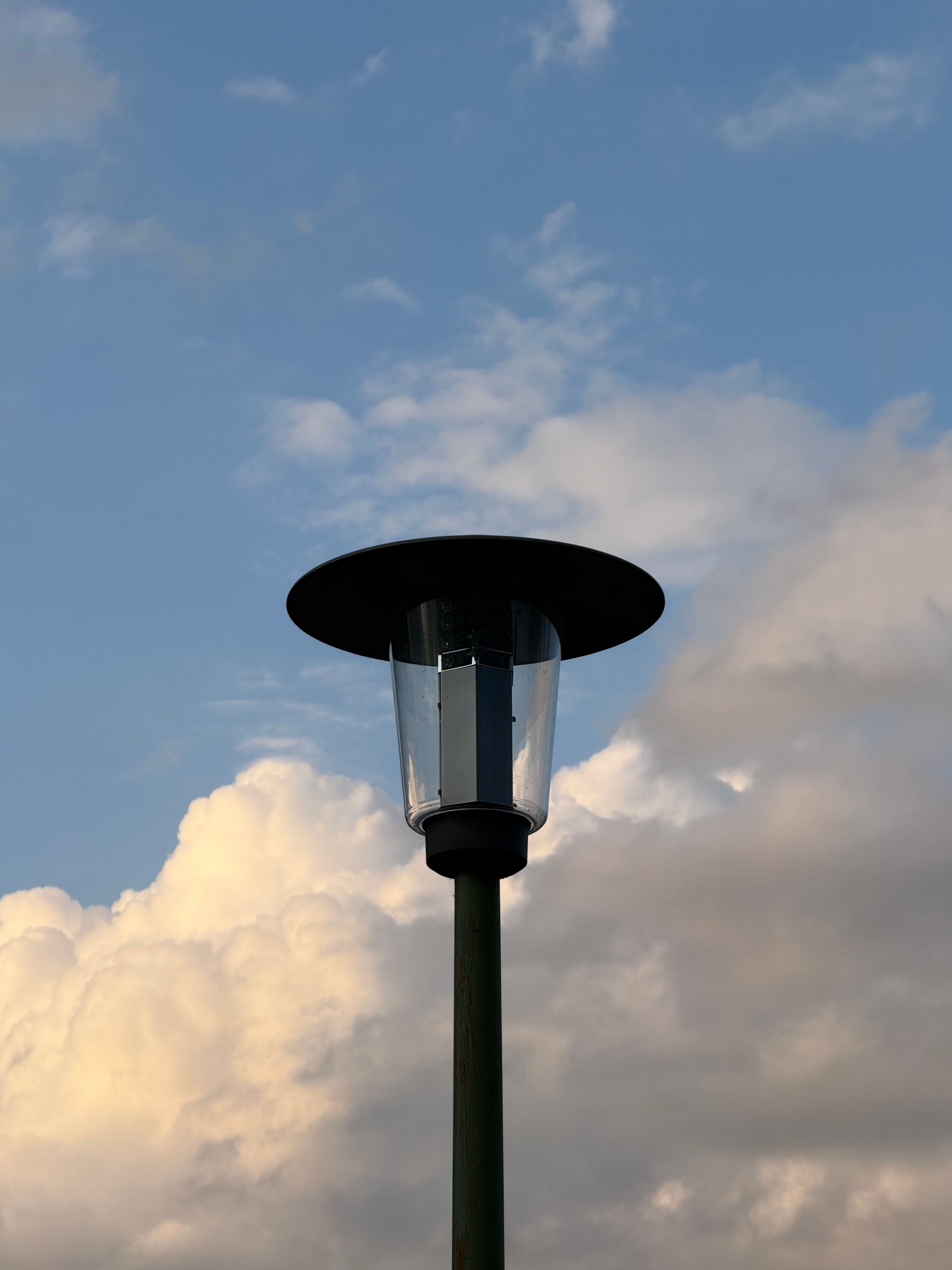 Street lamp silhouetted against a picturesque cloudy sky during the day.