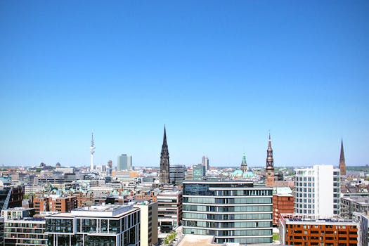 High-rise buildings under clear blue sky in Hamburg cityscape. by Sabine