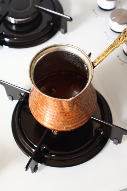 Free Overhead view of Turkish coffee being brewed in a traditional copper cezve on a stove. Stock Photo