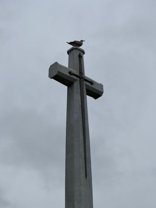 Free A solitary seagull sits atop a memorial cross against a cloudy sky in Halifax, Nova Scotia. Stock Photo