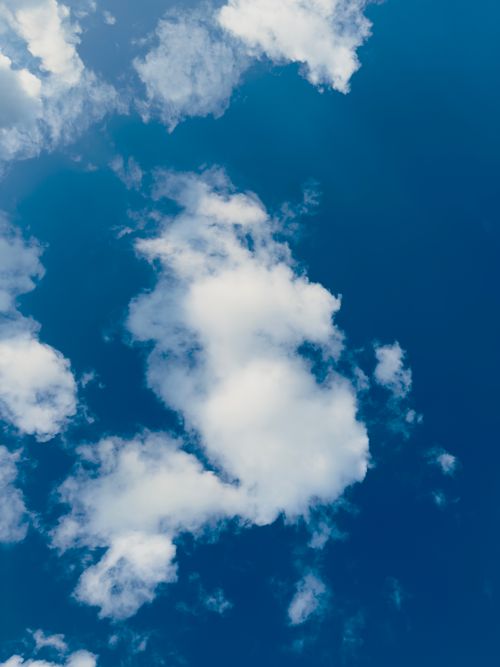 Free A serene view of fluffy white clouds drifting across a vibrant blue sky, perfect for depicting tranquility. Stock Photo
