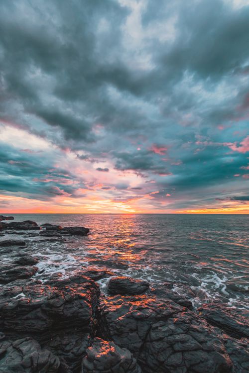 Free Striking sunset over rocky coast in Quảng Trị, Vietnam with vivid colors and dramatic clouds. Stock Photo