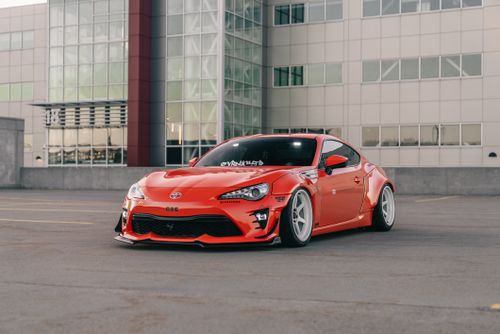 Free Sleek red sports car parked in front of a modern office building. Stock Photo