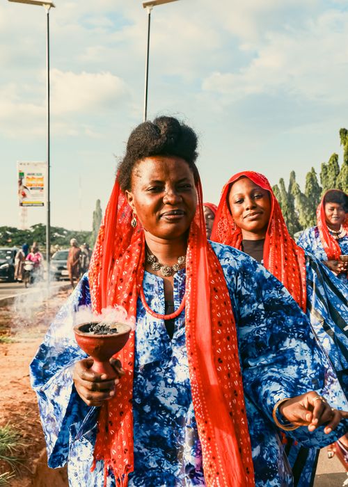 Free Women in colorful attire participate in a traditional ceremony outdoors, holding ceremonial items. Stock Photo
