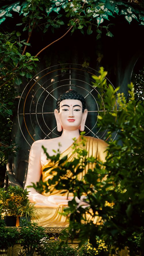 Free Golden Buddha statue surrounded by lush greenery in tranquil Ho Chi Minh City garden. Stock Photo
