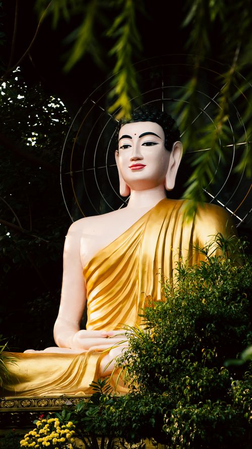 Free Peaceful Buddha statue draped in gold, nestled among lush greenery in Ho Chi Minh City, Vietnam. Stock Photo