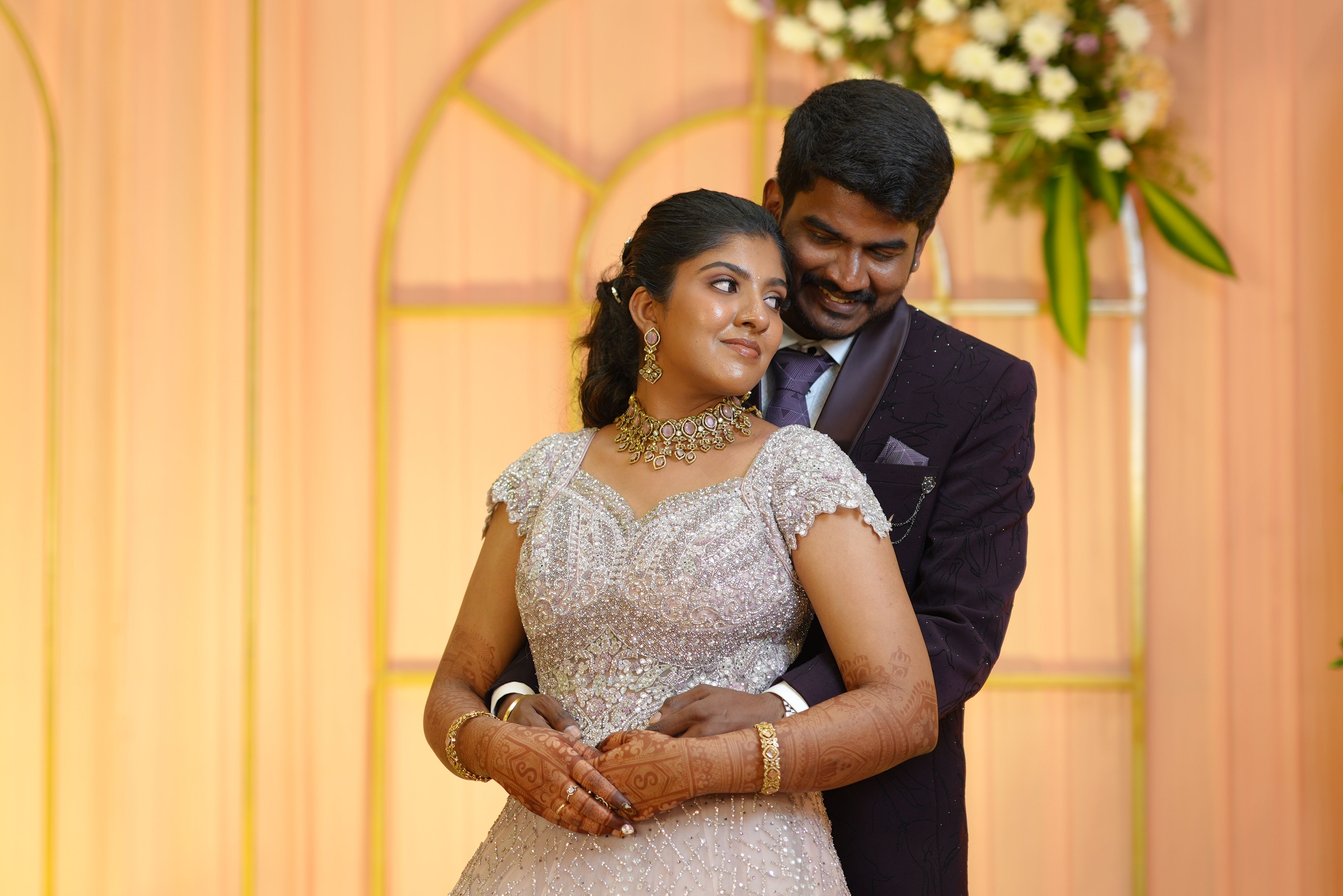 Beautiful couple in elegant attire at their wedding, embracing gracefully indoors.