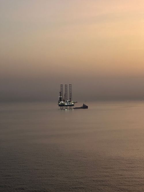 Free A tranquil scene of an offshore oil rig and ship during sunset in Saudi Arabian waters. Stock Photo