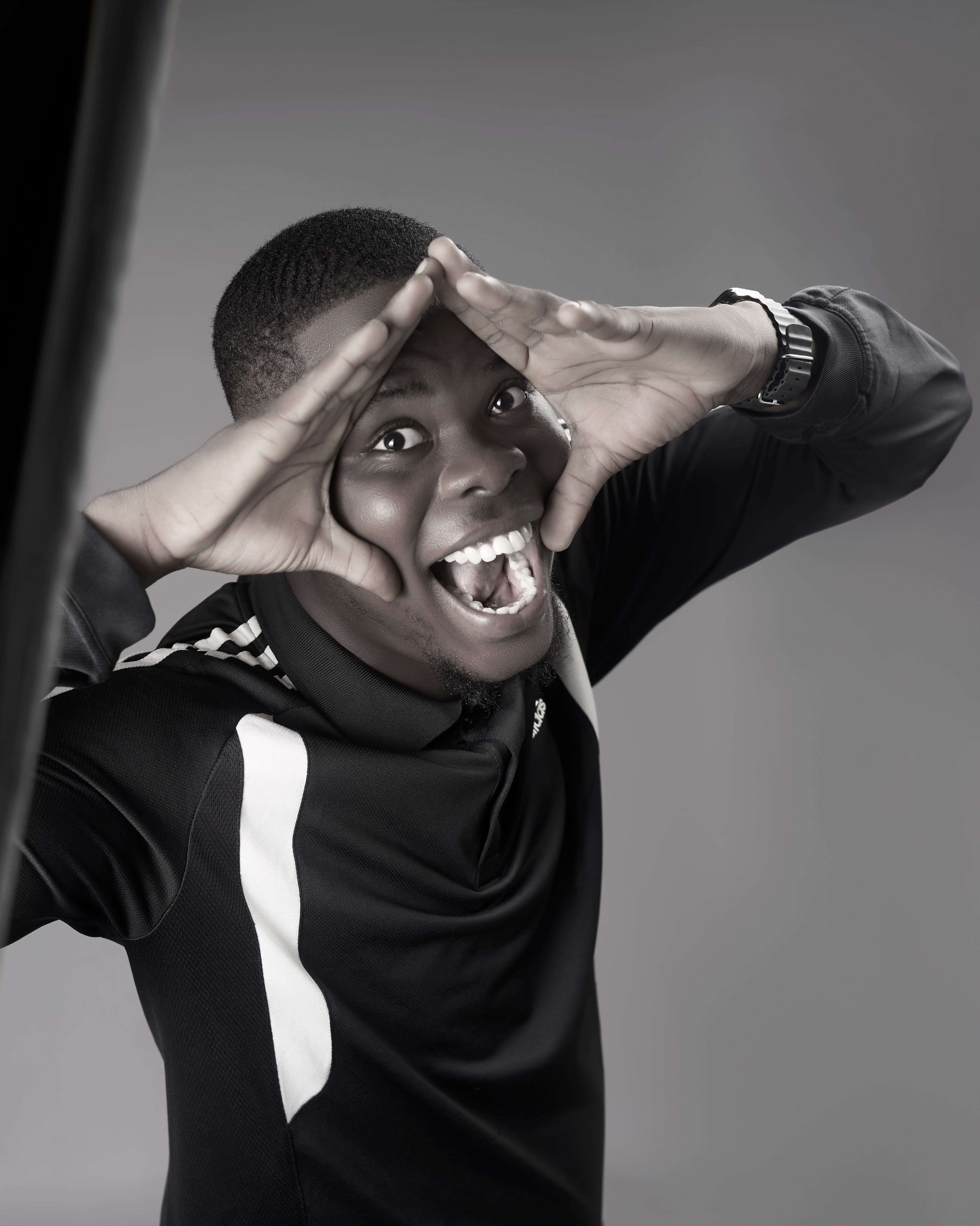 Energetic portrait of a young man making a playful pose in monochrome.