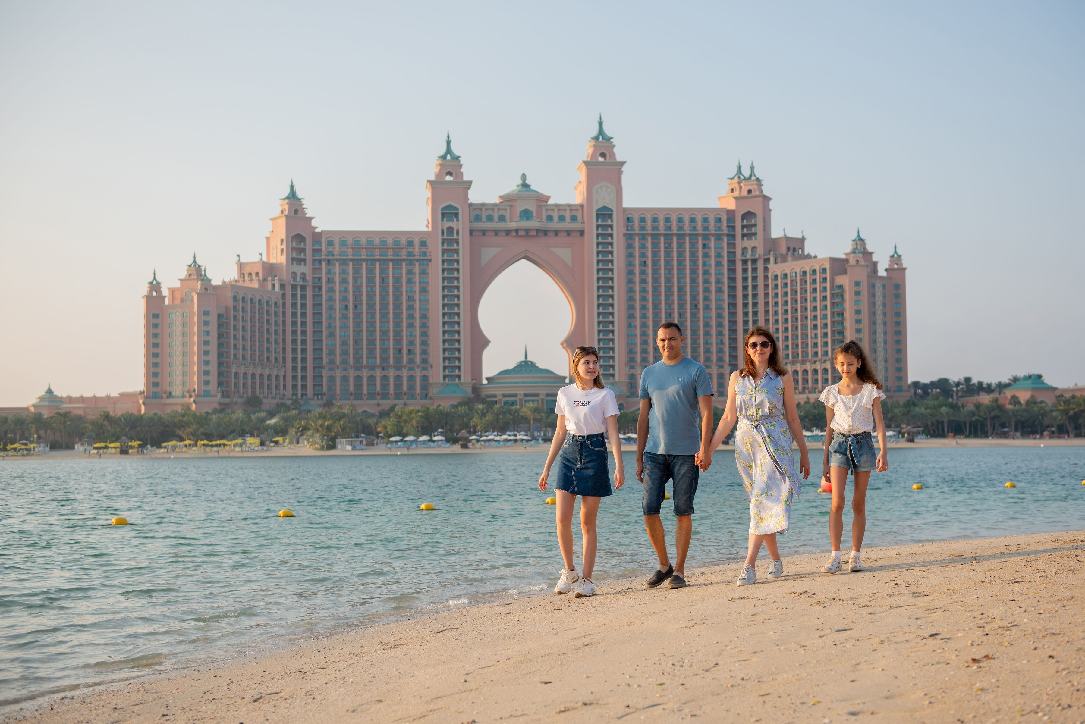 Family walking along the beach with Atlantis The Palm Hotel in the background, Dubai.