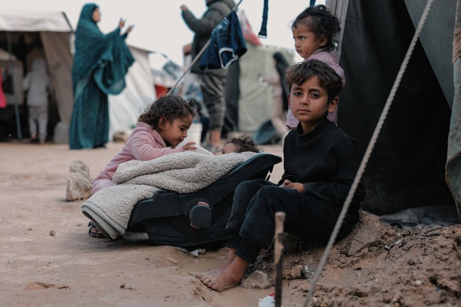 Children sitting in a refugee camp, highlighting human resilience amidst challenging conditions.