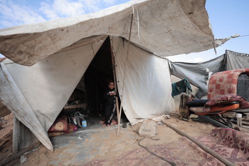 Free A young child stands outside a rugged tent in a sparse desert environment. Stock Photo