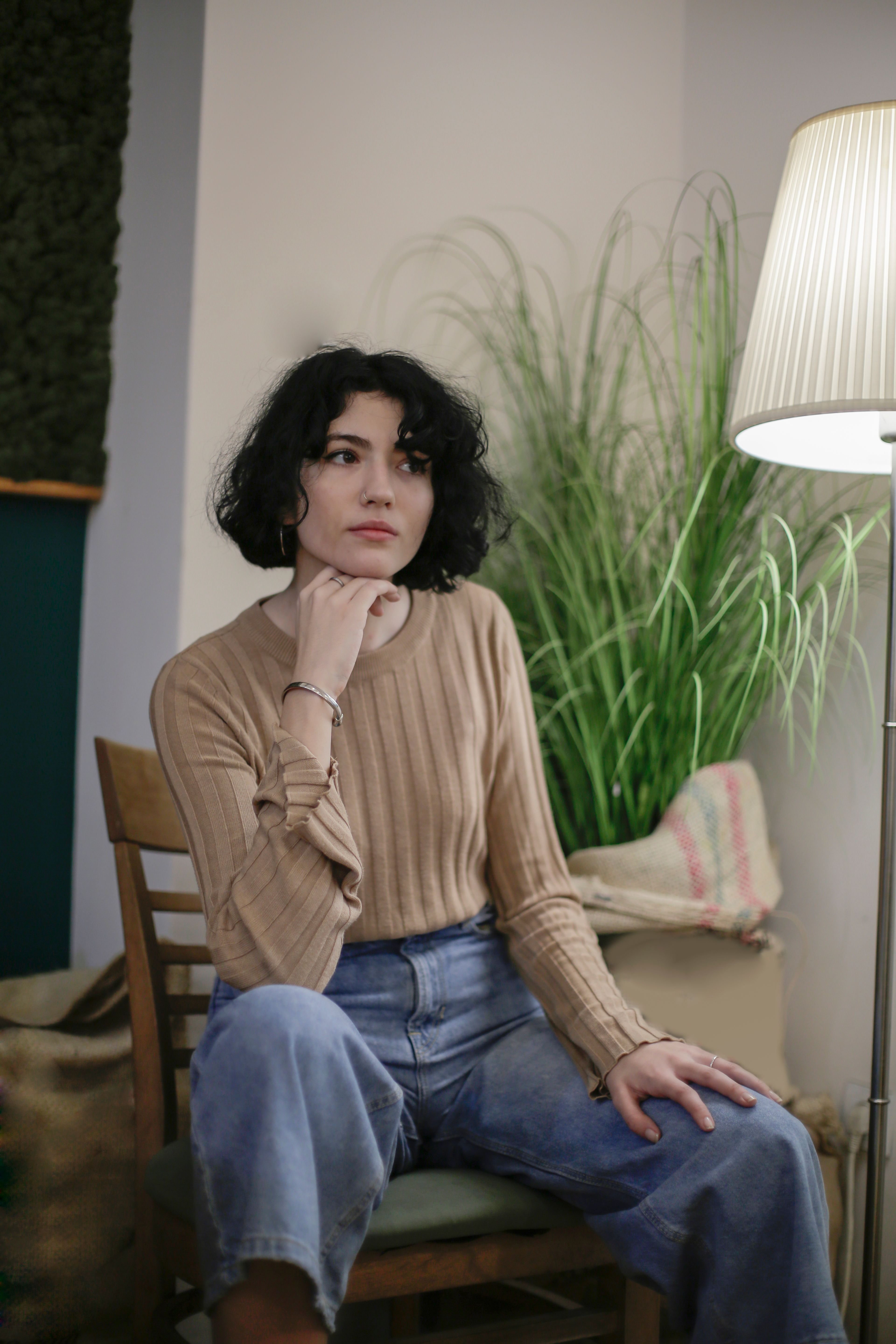 Woman in Beige Long Sleeve Shirt and Blue Denim Jeans Sitting on Brown ...