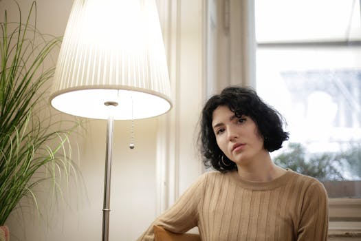 Young woman with short hair relaxing in a cozy room beside a lamp.