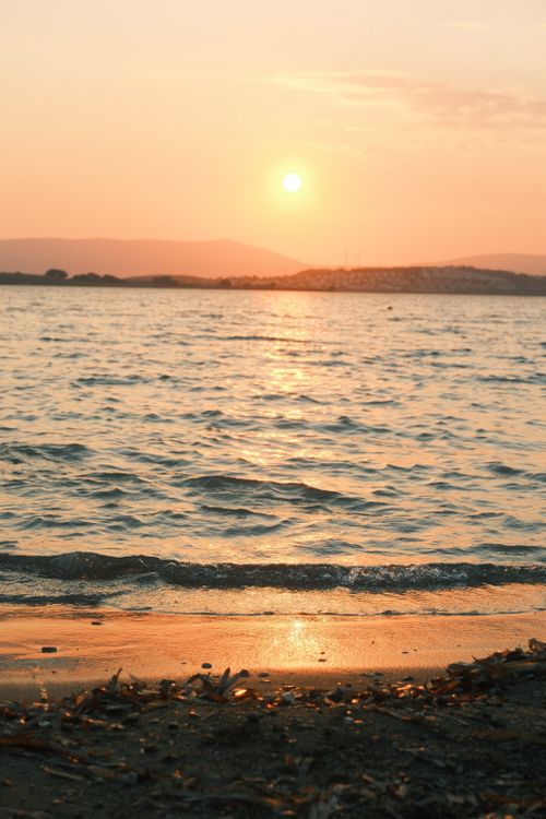 Free Calm beach at sunset with serene ocean waves and warm hues Stock Photo
