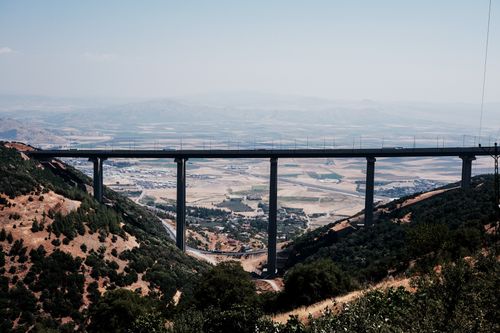 Free Dramatic bridge spanning a scenic mountain valley with rural landscape. Stock Photo