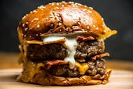 令人垂涎欲滴的双层芝士汉堡，搭配培根和酱汁，夹在芝麻面包里