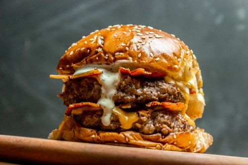 Free Mouth-watering double beef cheeseburger with bacon and cheese sauce. Stock Photo