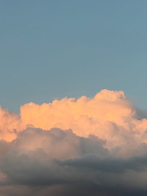 Free A stunning view of fluffy clouds illuminated by warm sunset light against a clear sky. Stock Photo