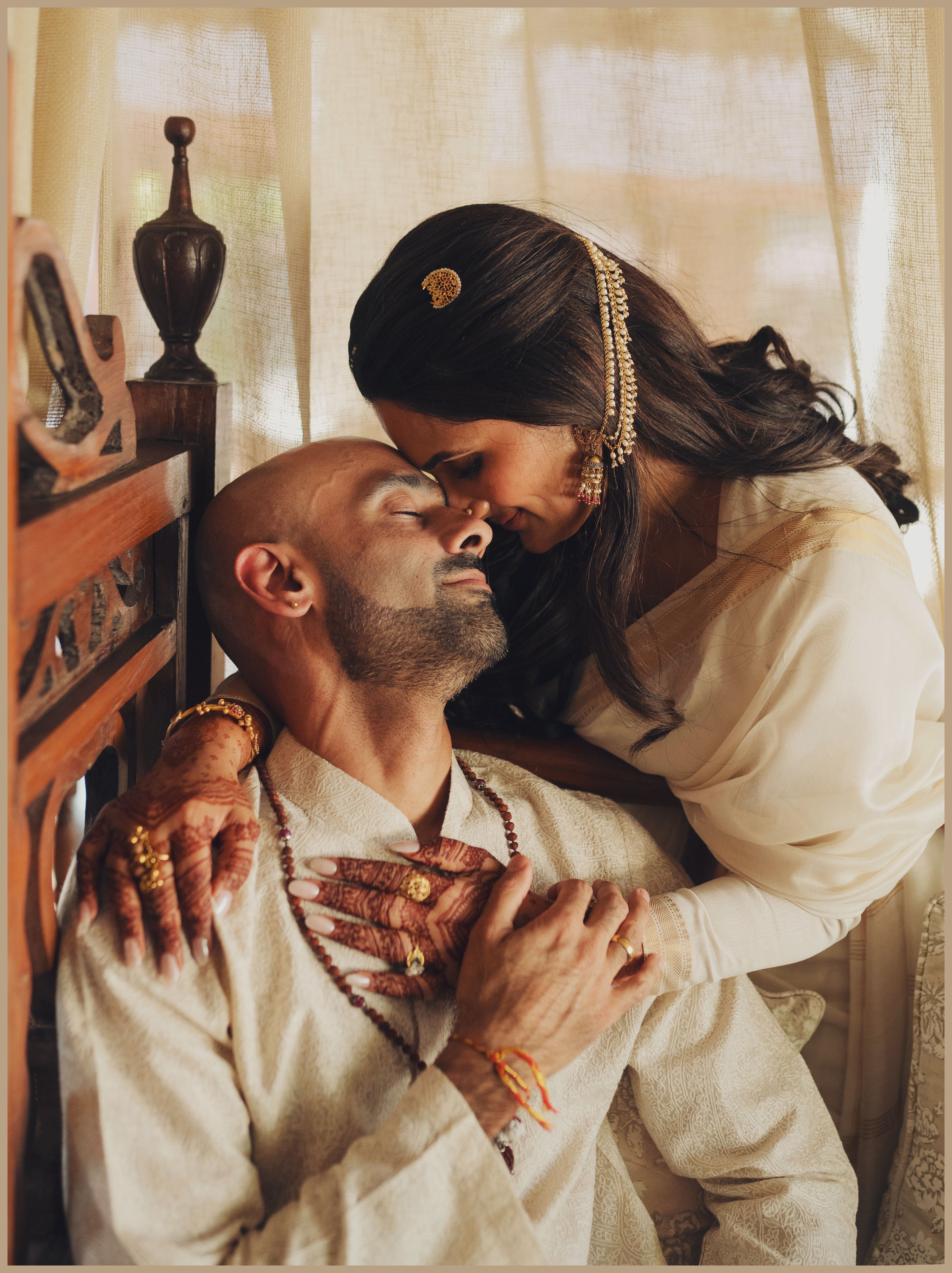 A loving couple sharing an intimate moment in elegant traditional attire indoors.