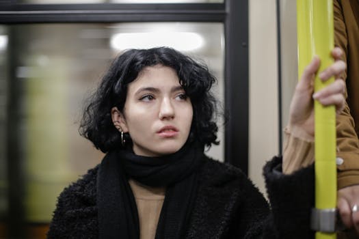 Portrait of a young woman with short hair holding a pole on public transportation.