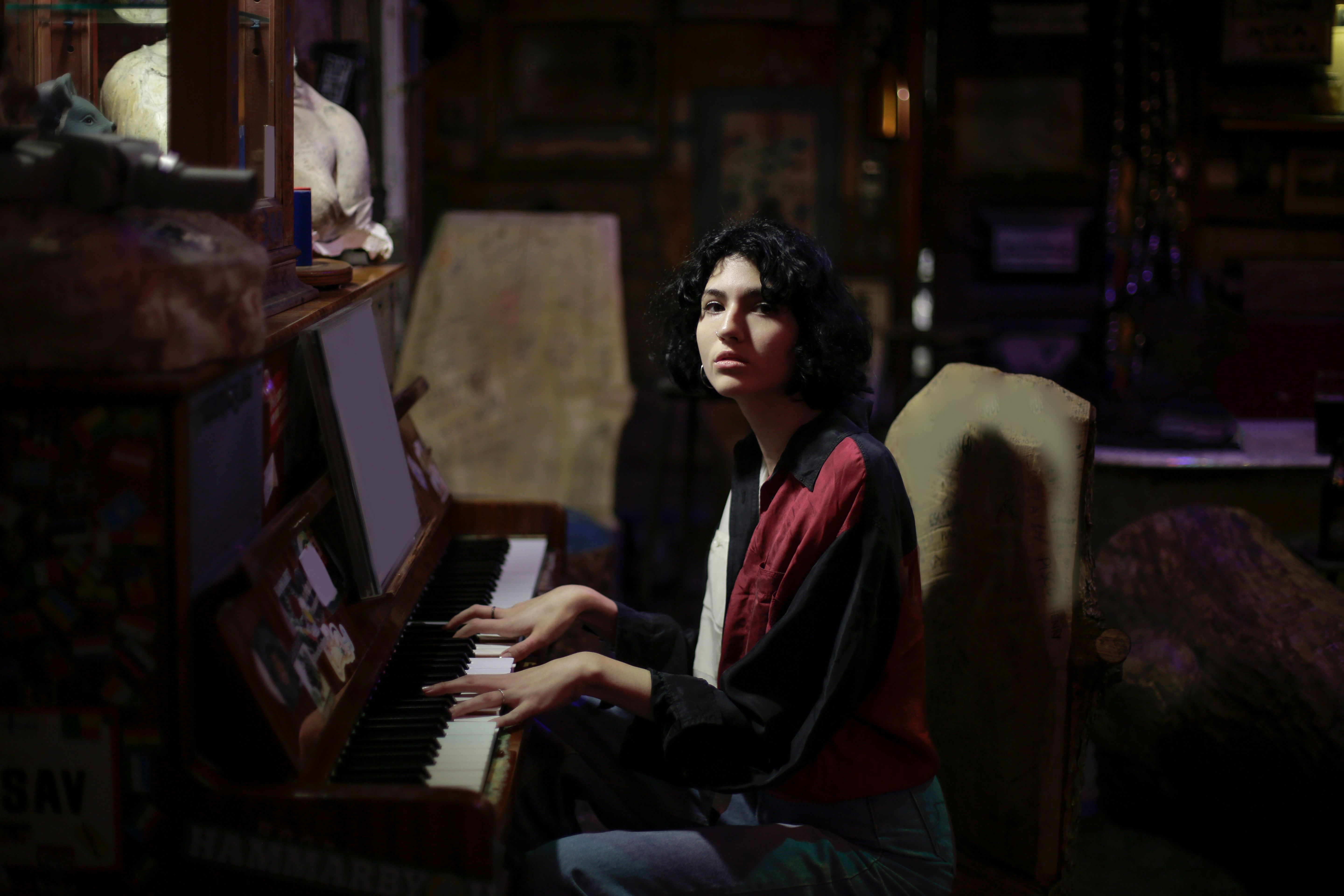 A dimly lit basement music studio with vintage instruments and posters